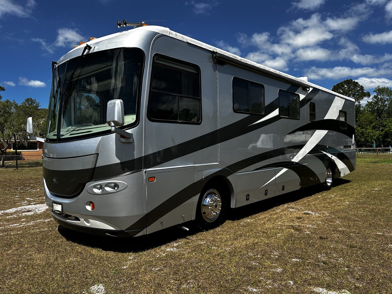 Class A diesel pusher motorhome parked in a sunny grassy lot