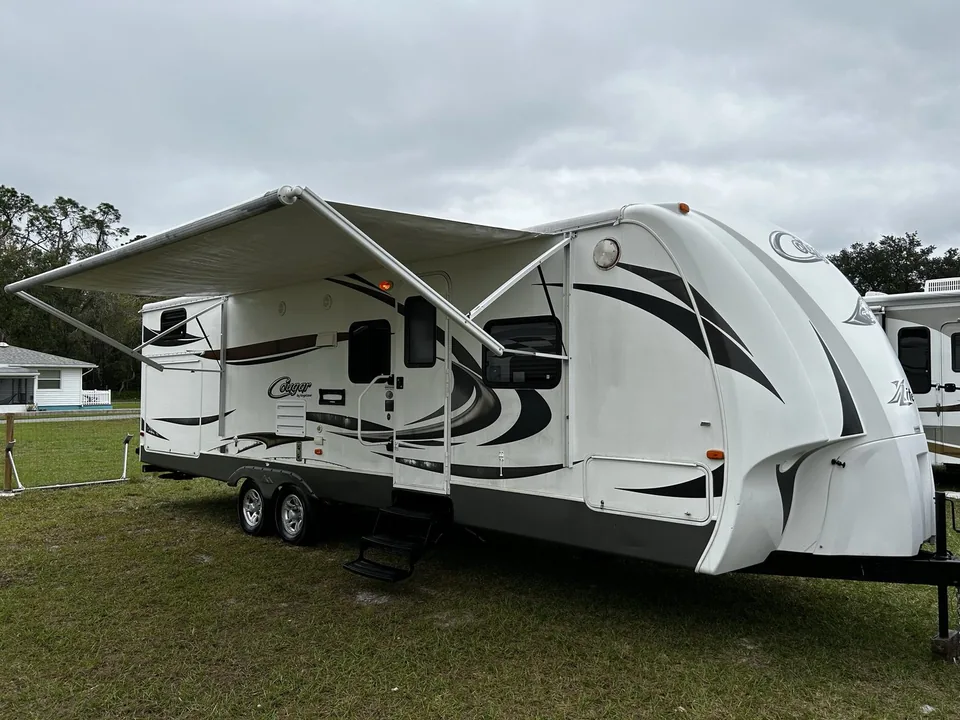 Travel trailer with the awning out at a Central Florida campsite, the kind of camper Niko buys before owners head north