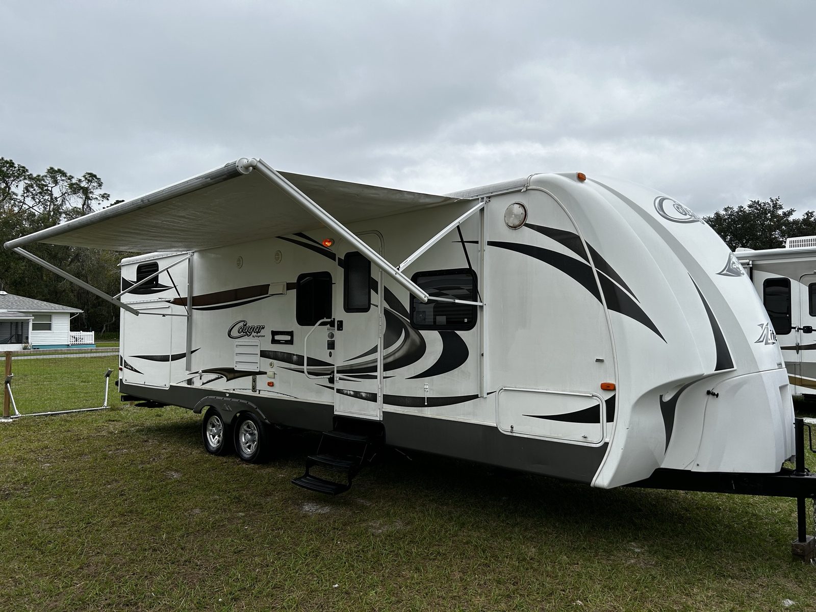 Travel trailer with the awning out at a Central Florida campsite, the kind of camper Niko buys before owners head north